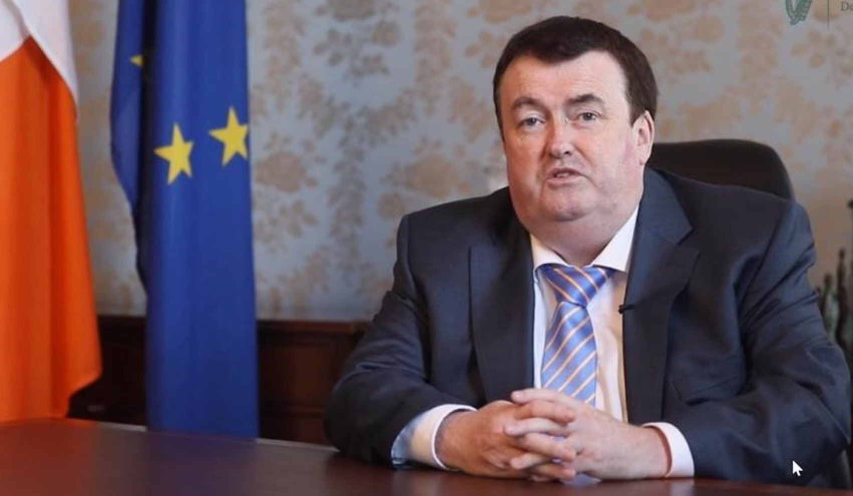 Minister Colm Brophy seated at desk beside Irish and EU flags